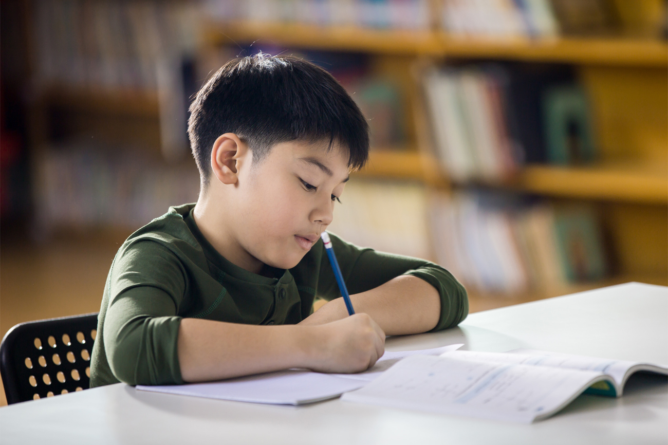 Happy asian child doing homework with smile face.